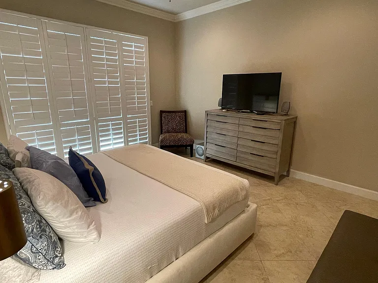 Master bedroom with new modern & elegant Cal-king platform bed, 8-drawer dresser, TV & chair.
