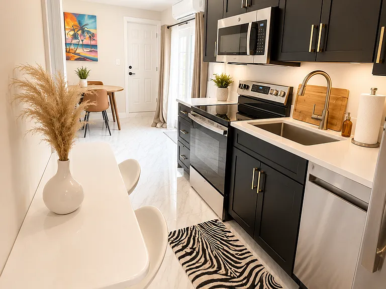 Stylish private guest suite kitchenette with modern black cabinets, sleek finishes, stainless steel appliances, sink, microwave, air fryer, coffee station, and everything needed for convenient short-term or extended Naples stays.