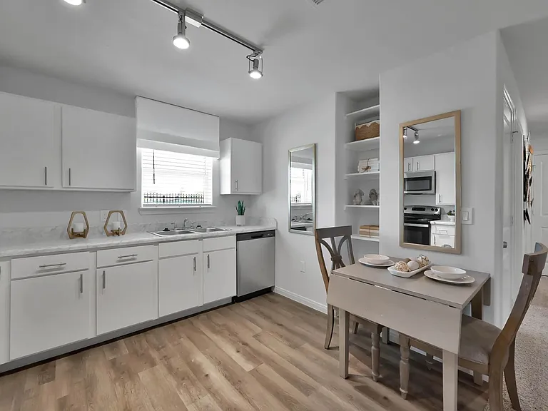 Enjoy modern living at Esperanza at Wild Orchid. This stylish kitchen features sleek white cabinetry, top-notch appliances, and an inviting dining space, perfect for gatherings. Schedule your visit today and make this your new home!