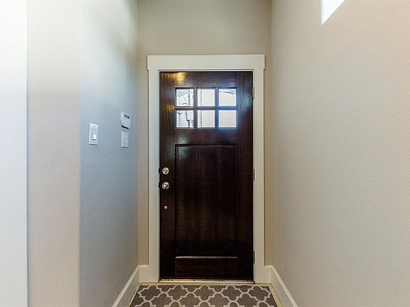 The solid wood front door opens into a light and bright entry with high ceilings and beautiful tiled floors. The entry hallway leads to a first floor bedroom and a door that leads to a covered patio and backyard.