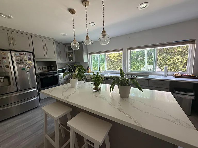 Spacious kitchen with quartz-style island seating, stainless appliances, ample cabinetry, and large windows over the sink.