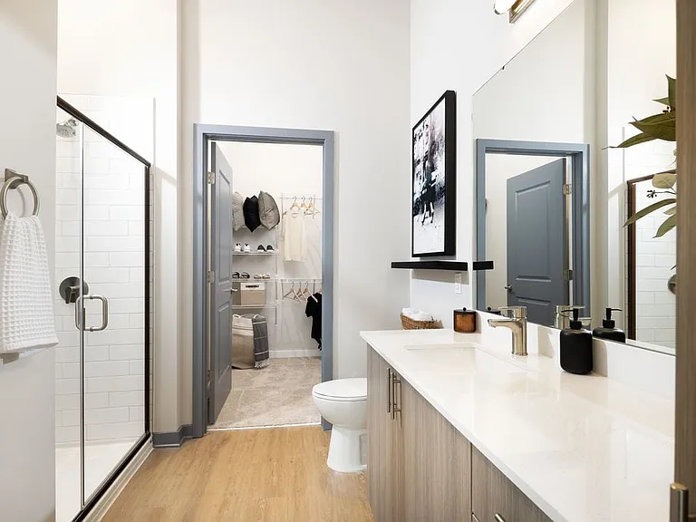 Primary bathroom with standing shower, oak cabinetry, white quartz countertops, and ample storage