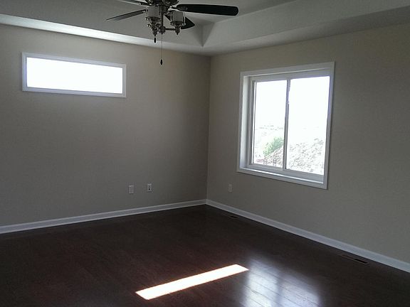 Living room with tray ceiling, ceiling fan, wood floors.