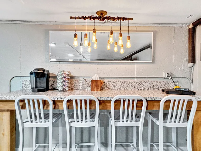 a kitchen with a long counter and white chairs Sunset Station Apartments Portland Oregon