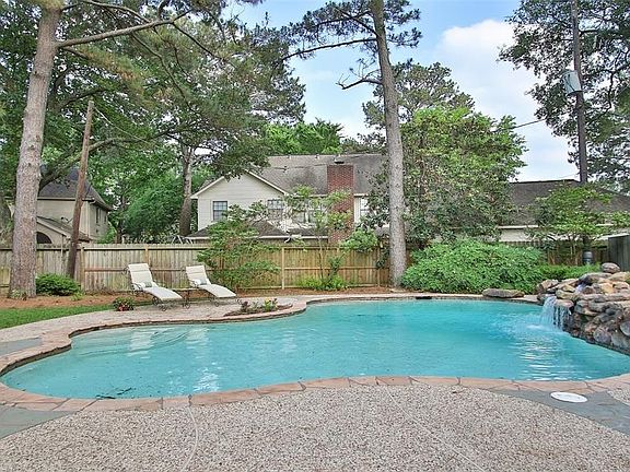 BACKYARD OASIS: Flagstone coping and a rock waterfall create a natural backdrop for this sparkling pool. Set on a lot that is almost 17,000 square feet, this backyard has plenty of space for pool, patio, yard space and gardening.