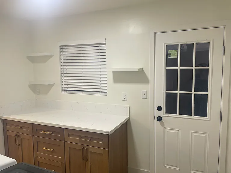 custom cabinetry, quartz countertop, utility sink, and wall-mounted shelves