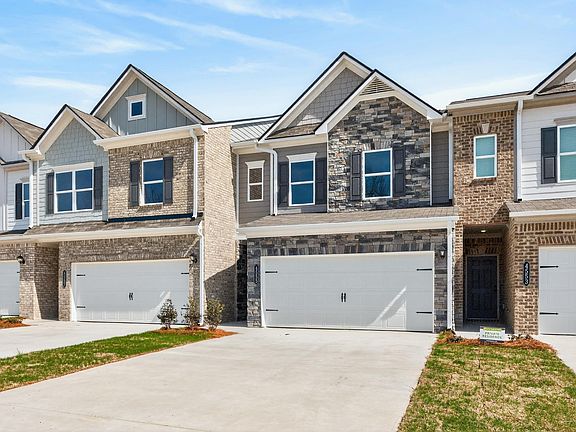 Craftsman house with board and batten siding, a garage, driveway, and stone siding