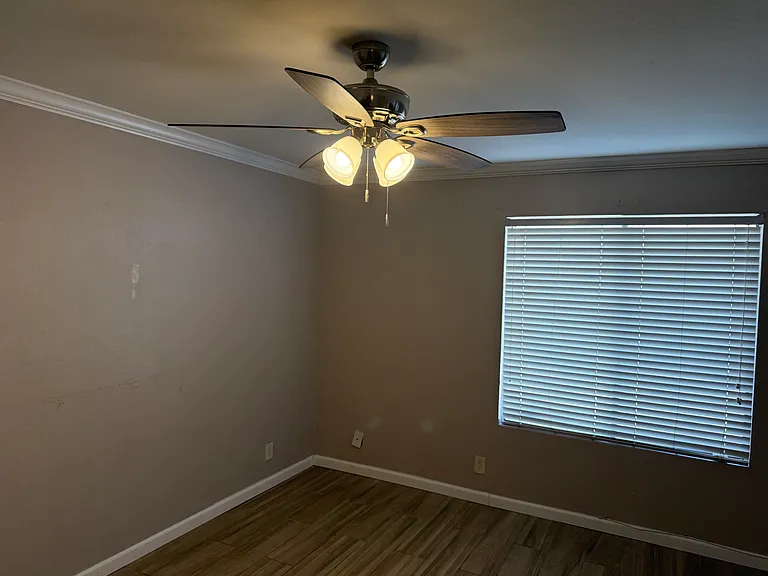 Primary bedroomwith lighted ceiling fan.