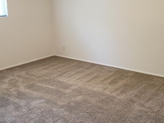 Larger Bedroom with tan carpet.