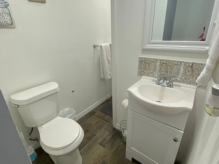 Spotless bathroom includes a mirror, sink, toilet, shower, towel racks, and essential supplies