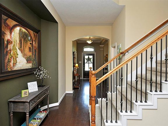 Lovely entryway with leaded glass front door beaming wide plank wood floors, great art niche, wrought iron spindles, arches and decorator colors.