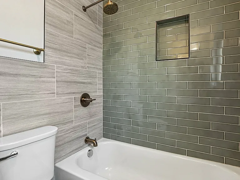 Sleek bathroom featuring a modern bathtub with elegant green subway tiles and stylish fixtures.
