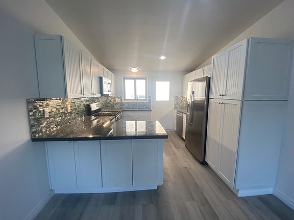 Gourmet kitchen with top of the line chrome appliances, blue granite countertops with beach glass backsplash, tons of soft close white cabinets and small back patio for BBQ or small table that has ocean view