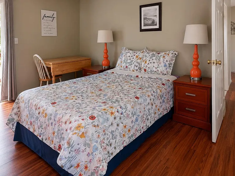 Inviting bedroom with a full bed, nightstands with lamps, and a writing desk, plus sliding-door access to a deck.