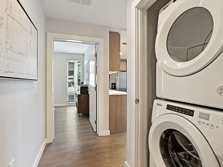 Hallway With Light Wood Hardwood Flooring And Washer/ Dryer