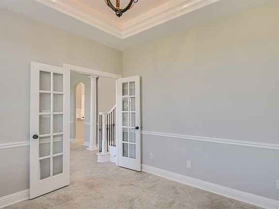 A view from the study, through the foyer and a peek into the kitchen. Notice the fresh neutral paint, matte black hardware and warm, contrasting chandelier.