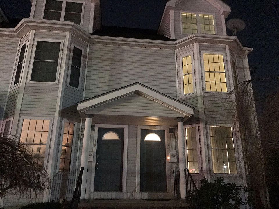 Front of House with professionally landscape front lawn, flowering trees and flowering shrubs.