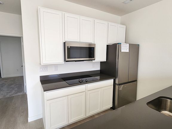 Back wall of the kitchen which is entirely new, upper cabinets, an induction cooktop (Samsung), full size refrigerator (Samsung), dishwasher (Samsung), a large space convection oven (Samsung) and a garbage disposal.