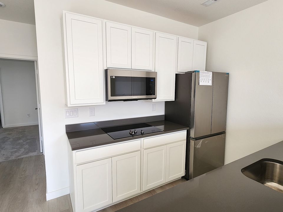 Back wall of the kitchen which is entirely new, upper cabinets, an induction cooktop (Samsung), full size refrigerator (Samsung), dishwasher (Samsung), a large space convection oven (Samsung) and a garbage disposal.