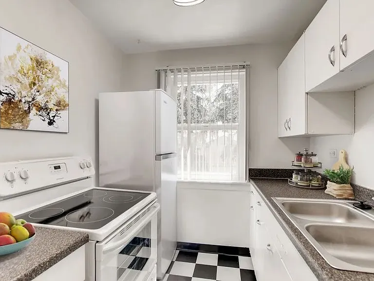 Kitchen with stove fridge sink cabinets and black and white tile floor with window in back