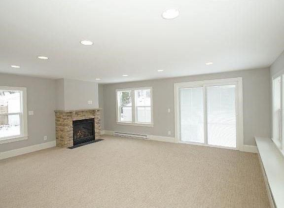 Large family room on the main level with recessed lighting and a stone gas fireplace.