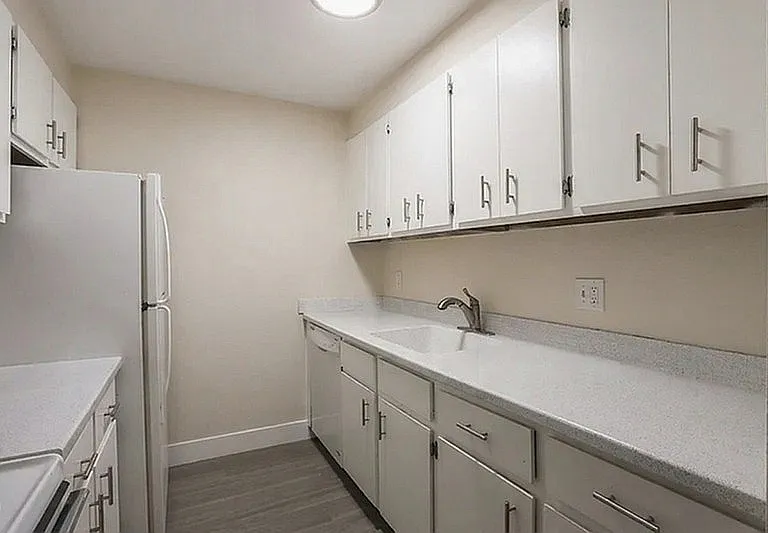 Sleek and modern galley kitchen with ample white cabinetry and spacious countertops, perfect for culinary adventures.