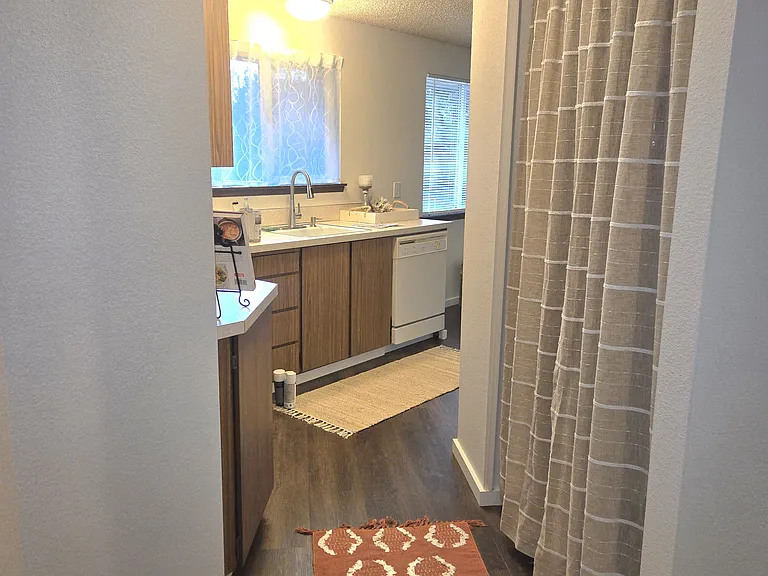 View from bathroom of galley kitchen/laundry (pictured on right). (laundry room curtains, rugs, and staging items not included).