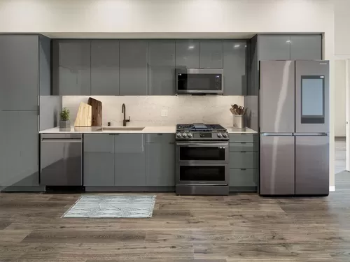 Upgrade Package Kitchen with grey cabinetry, undercabinet lighting, marble backsplash and countertop, and black stainless steel appliances - AVA Arts District