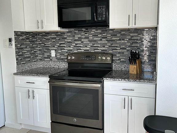 Fully equipped kitchen with stove, oven, microwave, fridge, and ample cabinets.