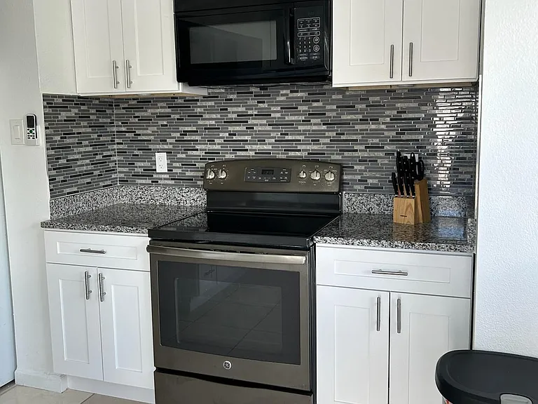 Fully equipped kitchen with stove, oven, microwave, fridge, and ample cabinets.