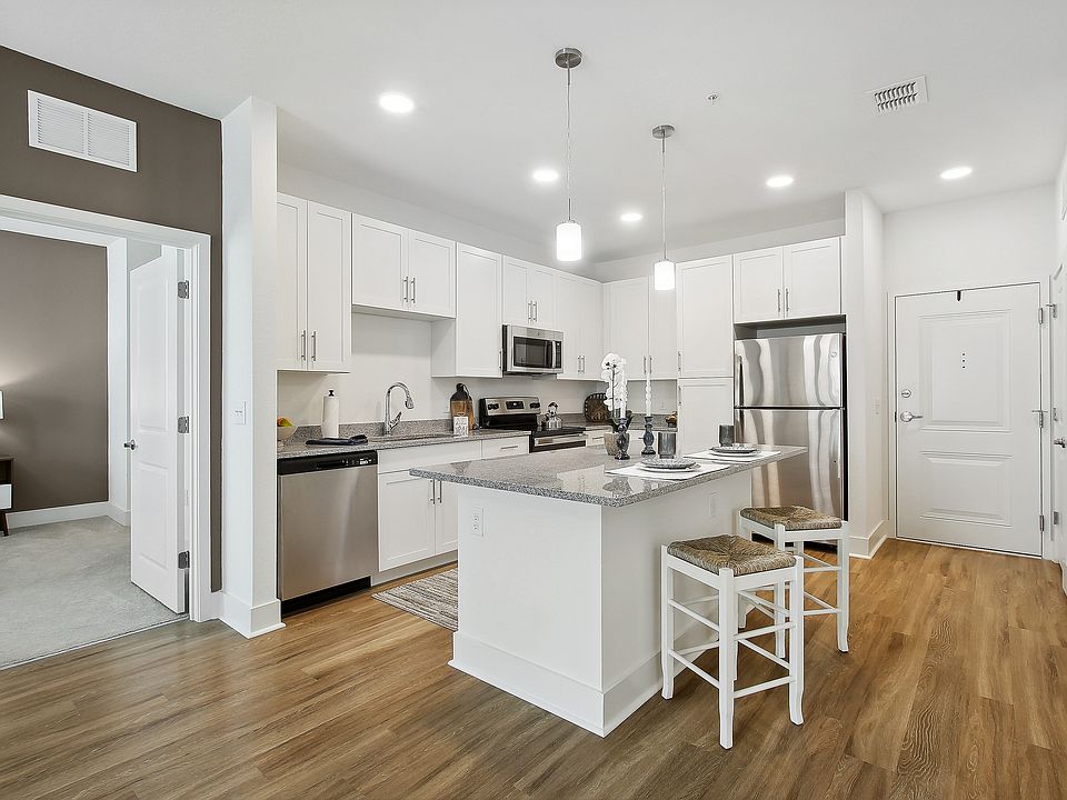 Modern kitchen with stylish white cabinetry, stainless steel appliances, and a cozy breakfast bar in an open-concept apartment.