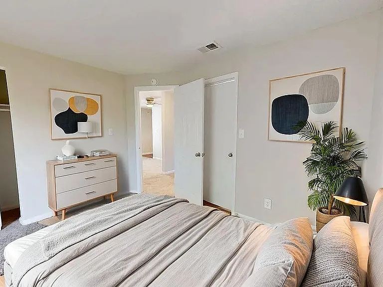 Modern bedroom with minimalist decor, featuring a cozy bed, stylish dresser, and abstract wall art.