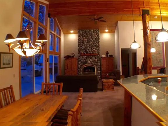 Great room living room area. TV in armoire. Gas fireplace. Long dining table in the foreground.