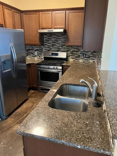 Kitchen with stainless steel appliances, granite counter tops with direct view of first floor living area. - 1410 Zephyr Ln