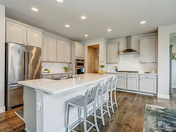The upgraded chef's kitchen has plenty of cabinet space, grey veined quartz countertops, and a stylish counter depth refrigerator.