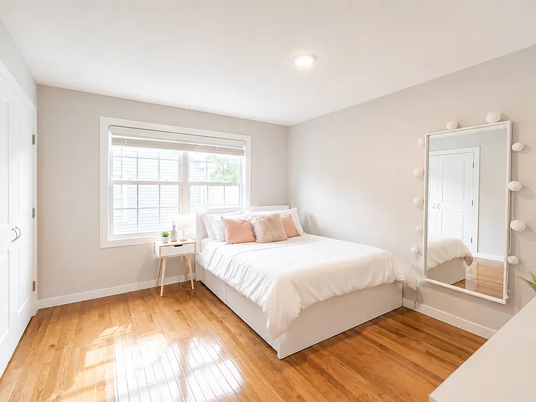 Bright bedroom with hardwood floors, large window, and ample closet space