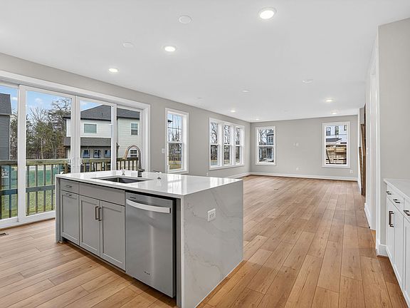 A modern, open-concept kitchen with a central island, hardwood floors, and large windows overlooking