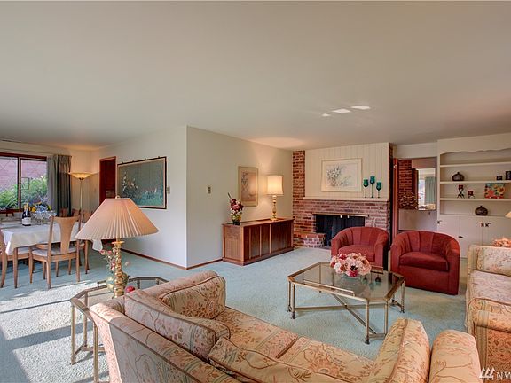 Large and open living and dining room with wood-burning fireplace and built-in bookshelves.