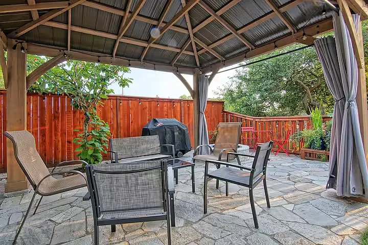 Cute backyard with a large bbq and two sets of outdoor furniture.