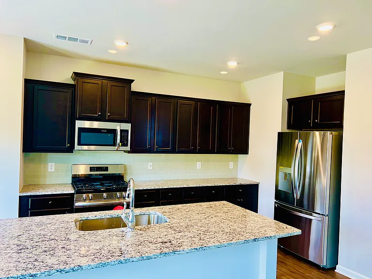 Espresso cabinets with Stainless Steel Appliances and larger Granite Island