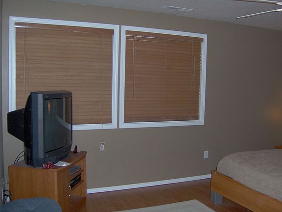 Spacious master bedroom with two windows and wood blinds