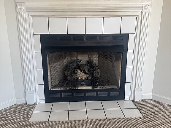 This white fireplace serves as the stunning focal point of the room, blending classic charm with modern simplicity. Its crisp, clean lines are beautifully highlighted by the natural light streaming in.