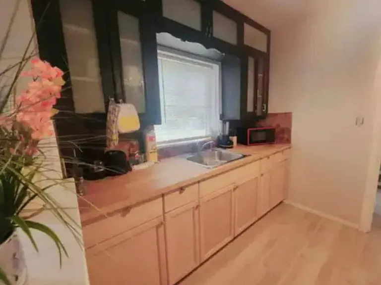 Kitchen counter run with ample cabinetry, double-basin sink, and a window over the workspace for natural light.