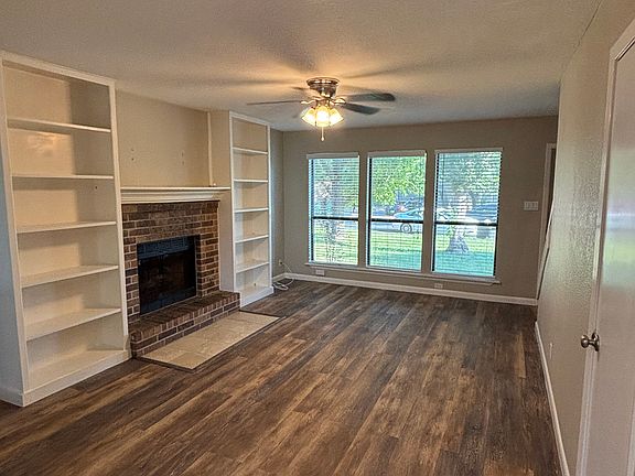Living area with fireplace, large windows, and built-in shelves