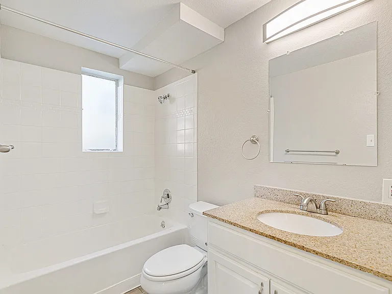 Bright and inviting bathroom with elegant granite countertop, modern fixtures, and a sleek bathtub.
