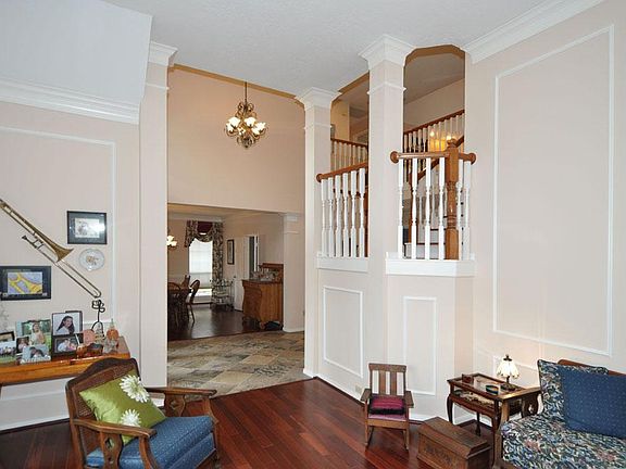 Formal living with Brazilian  cherry engineered wood flooring, crown moulding, and open spindle staircase.