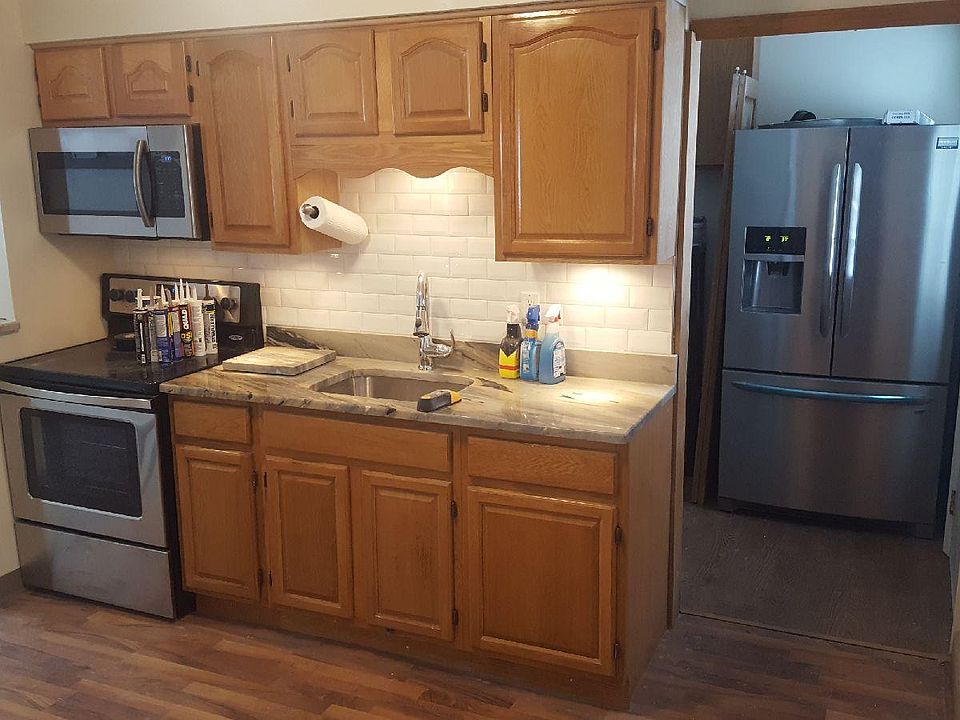 Galley eat in kitchen with granite, stainless appliances and tile backsplash