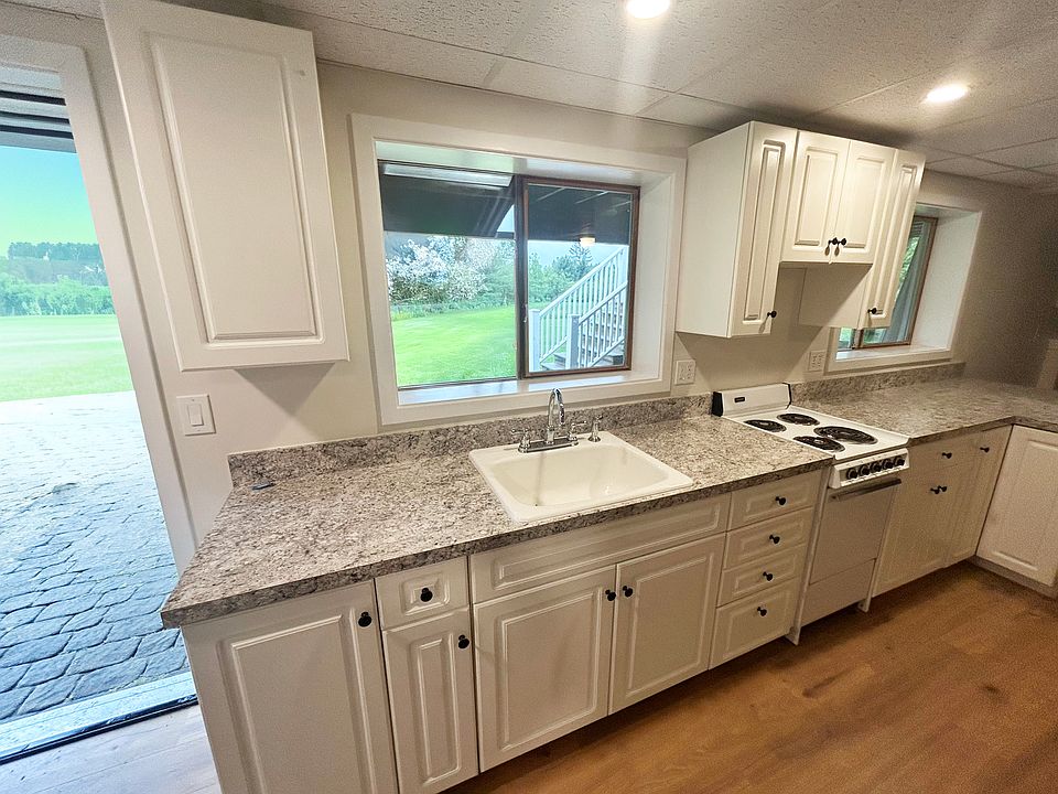 Kitchen view with ample counter space and two large windows. Entrance to apartment show on left (door is open)