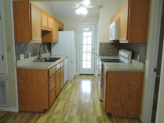 Galley kitchen with French door that opens to the covered porch. The hallway to the left has a large linen closet.