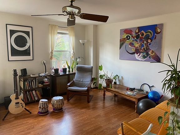 Sunny living room with wooden flooring. Ceiling fan included.